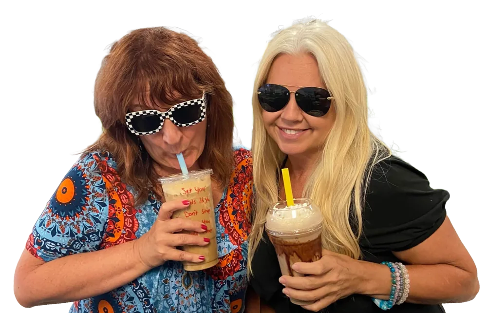 Two friends in sunglasses laughing with their Good Vibes drinks.